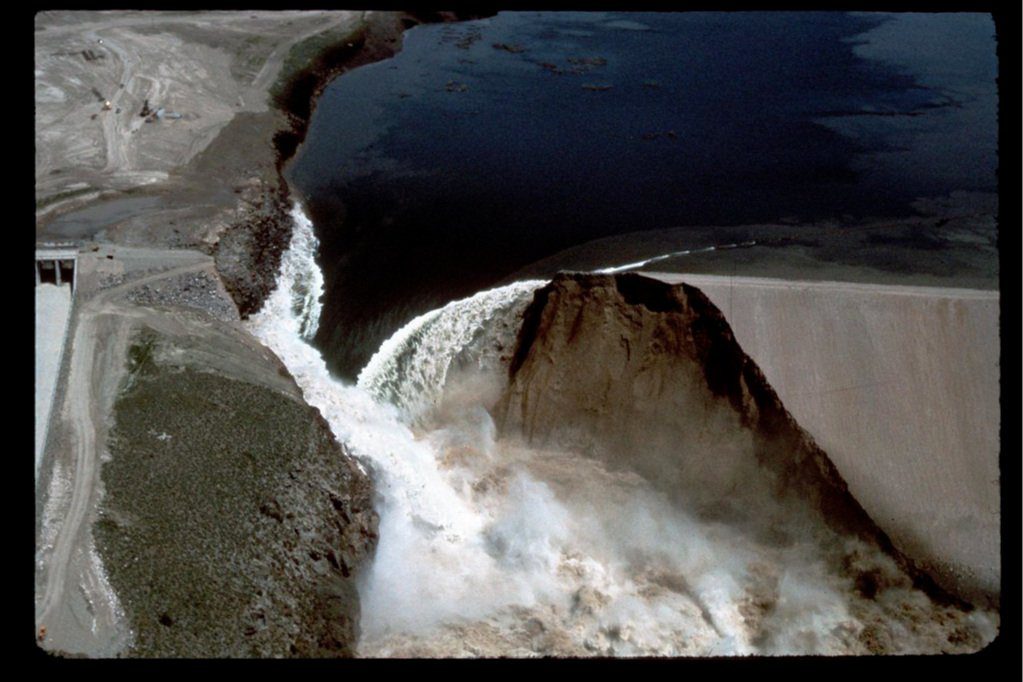 Aerial view of water forcefully cascading over a breached dam
