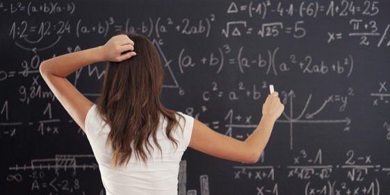 Woman writing math equations on a blackboard.