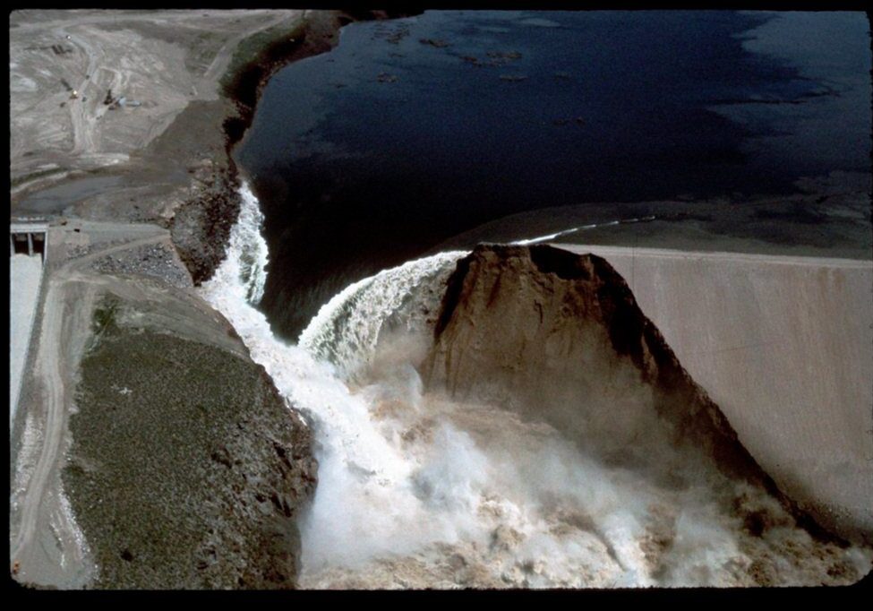 Aerial view of water forcefully cascading over a breached dam