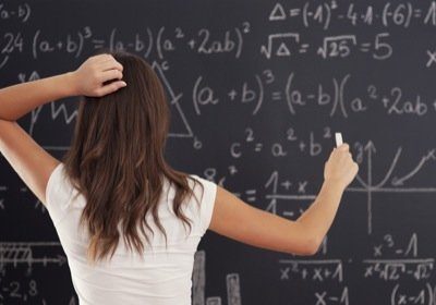 Woman writing math equations on a blackboard.