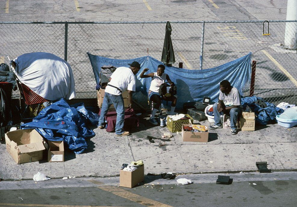 Four people sitting near a chain-link fence.