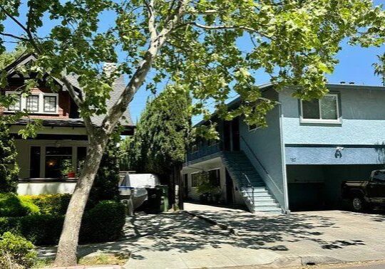 Two homes with a tree in the foreground.